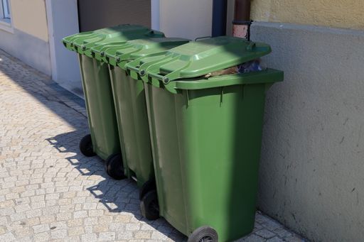 The green garbage cans leaned on the wall