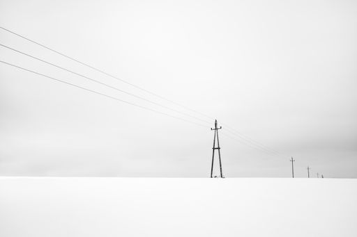 A lineup of overhead power lines in the middle of a winter scenery