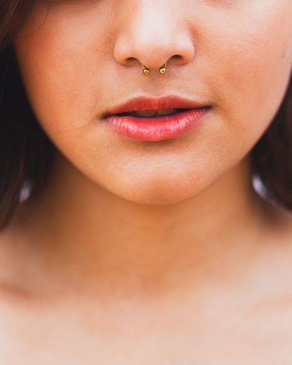 A close up portrait of a girl with a gold septum piercing