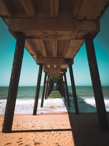 A vertical shot of a pier on the sea surrounded by a beach under the sunlight in Rio de Janeiro, Brazil