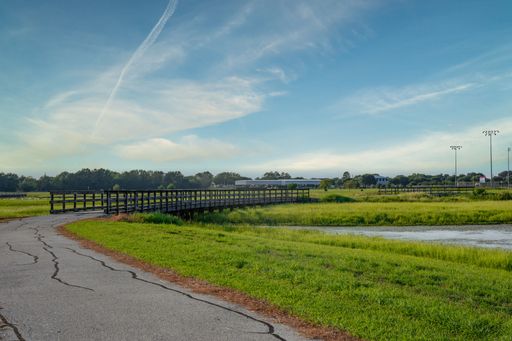 The view of a bridge over the river passing through the green fields under the blue sky