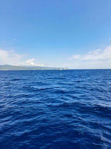 A vertical shot deep blue ocean water with a beautiful landscape in the background