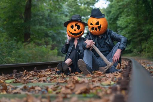 A closeup shot of a couple wearing pumpkins on their heads in the forest