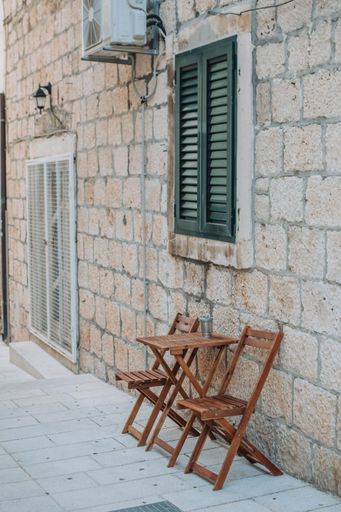 A vertical shot of a stone wall of a house and a wooden folding table set in front of it