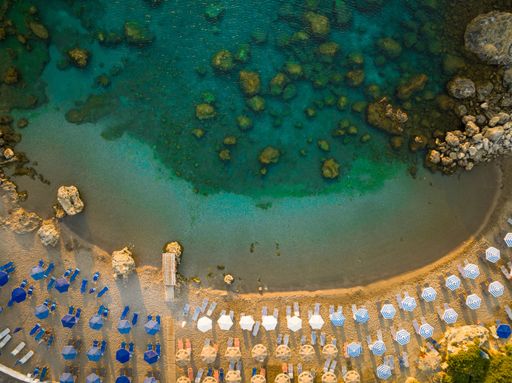 An aerial top view of beach chairs and umbrellas on a sandy beach
