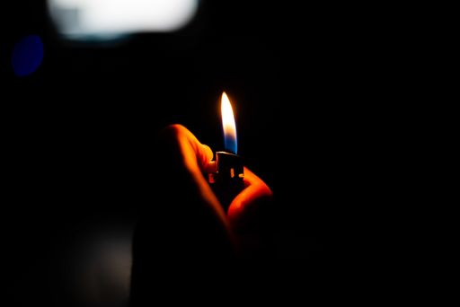 An abstract shot of a person holding a lit lighter in a dark room