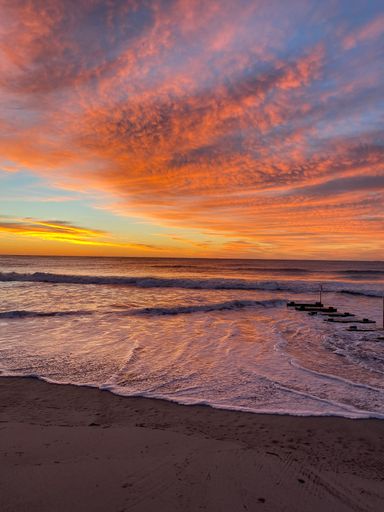 A vertical shot of a sandy beach and the sea captured at a beautiful sunset