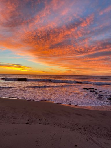 A vertical shot of a sandy beach and the sea captured at a beautiful sunset