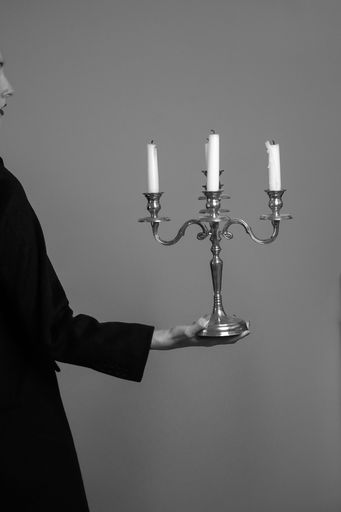 A vertical greyscale shot of an attractive female posing with a candleholder