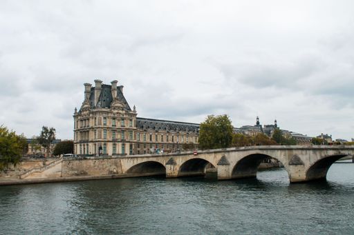 The Pont Royal bridge over the river Seine with the Pavillon de Flore in the background under a cloudy sky