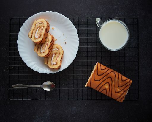 A top view of biscuit roll and cup of milk