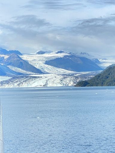 A vertical shot of Alaska fjords with a blue seascape in cloudy sky background in winter