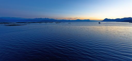Late evening sunset near the harbour of Molde in Norway with a ferry ship against deep blue water and a deep blue sky