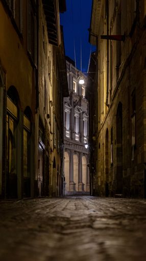 A vertical shot of narrow street of upper Bergamo city with old buildings at night in Italy