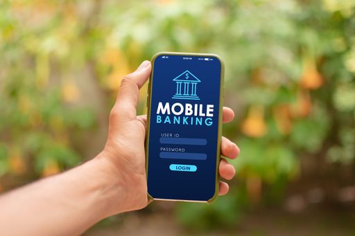 A close-up shot of a man holding a smartphone in his hand demonstrating a mobile banking app on the screen
