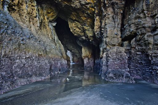 Inside view of Piha Blowhole cave channel dry with king low tide and unusually high sand deposit allowing walk through