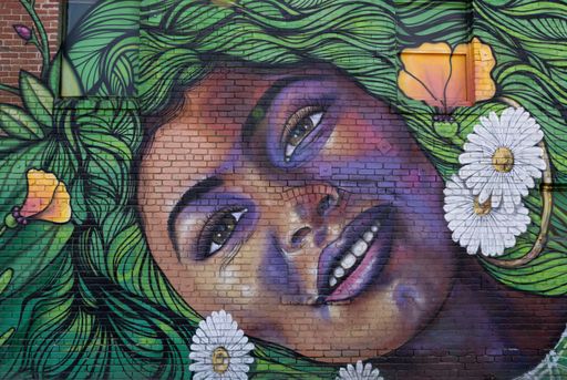 A wall mural of a beautiful green haired young woman in a street of Sacramento