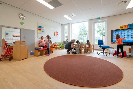 ARNHEM / NETHERLANDS - AUGUST 28 2020: Children in kindergarten play with toys. Other toys stored in cupboards, boxes and crates.