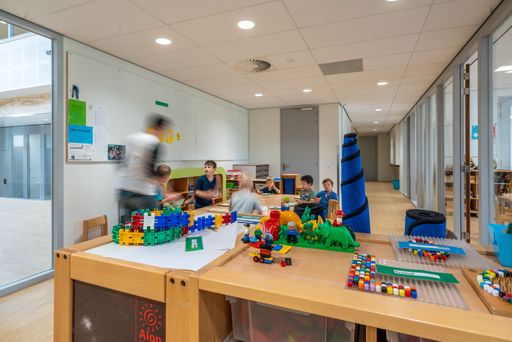 ARNHEM / NETHERLANDS - AUGUST 28 2020: Children in kindergarten play with toys. Other toys stored in cupboards, boxes and crates.