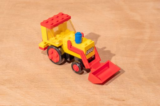 A closeup shot of a vintage Lego model of an excavator placed on a wooden surface