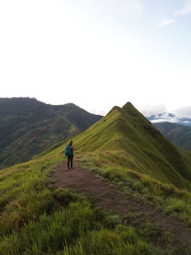 A vertical shot of a young man walking in the mountains