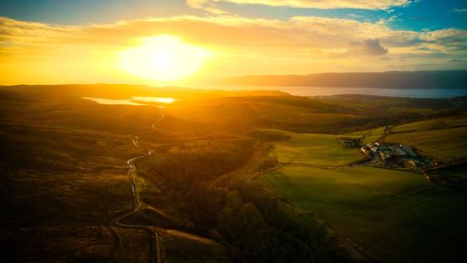 An aerial view of River Clyde flowing through the mountains in Scotland at sunset