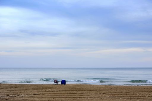 A view of a peaceful sea with beach chairs on the sand