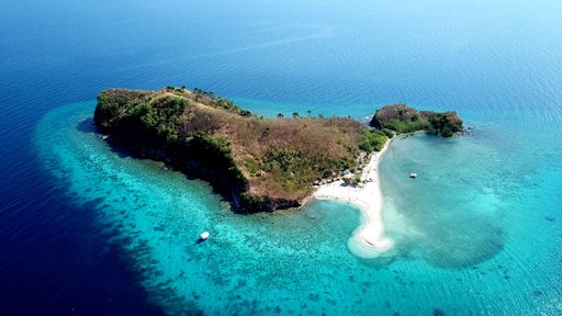 Aerial top view of the scenic seascape, lagoon and coral reef with turquoise water, small waves before storm on island in Philippines