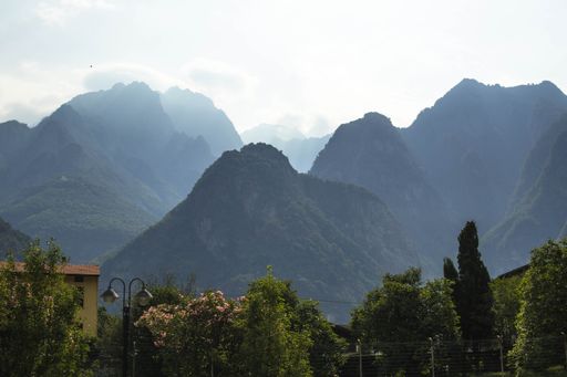 A landscape of green bushes on lawns under foggy green mountains