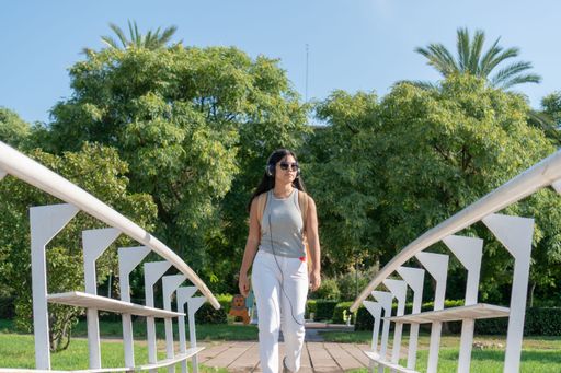 An asian girl listening to music with headphones in park