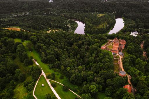 An arial shot of the Turaida castle in the left surrounded by many trees and rivers