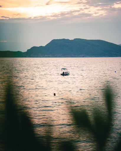 A vertical shot of a sea and a boat in the middle during the sunset