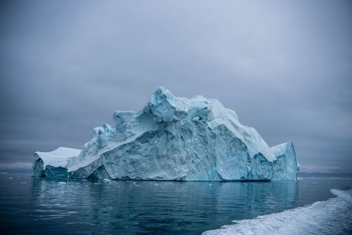 A piece of an iceberg floating in a frozen water under a blurry sky