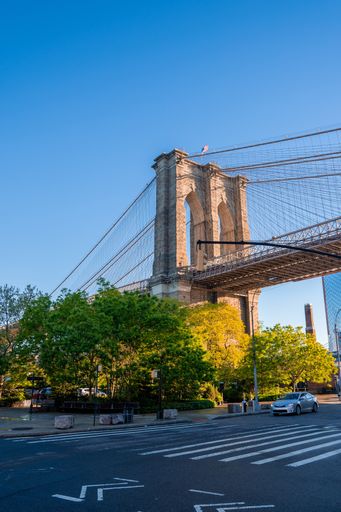 A vertical shot of Brooklyn Bridge over East River viewed from New York City Lower Manhattan waterfront in the morning