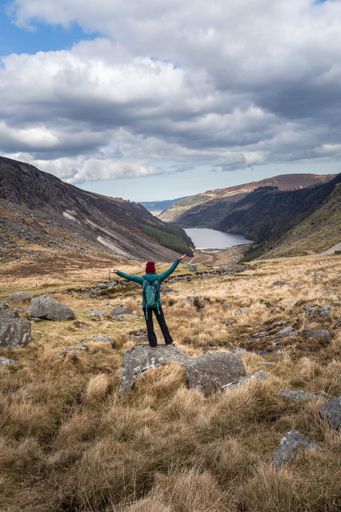 The woman standing on a rock, enjoying the beautiful landscape. Glendalough, Wicklow, Ireland.