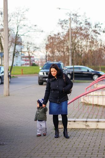 Woman walking with child holding hand on a sidewalk on the Stare Zegrze area
