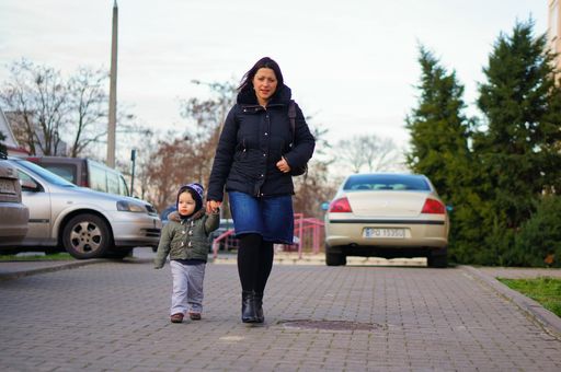 Woman walking with child holding hand on a sidewalk on the Stare Zegrze area
