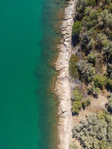 A vertical aerial of the turquoise water of the sea at the shoreline of a beach in Lesvos, Greece