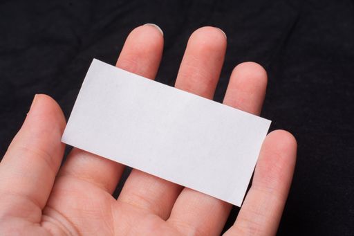 A closeup macro shot of a person holding a blank piece of paper