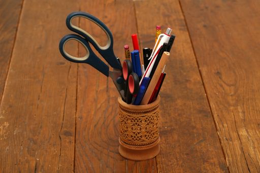 A closeup shot of pens and scissors in a holder