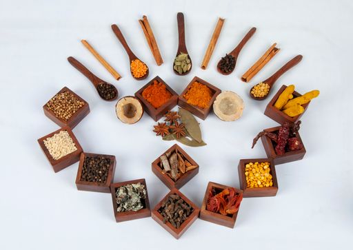 A top view of flavorful and spicy Indian spices served in wooden boxes and spoons with masala tea mix