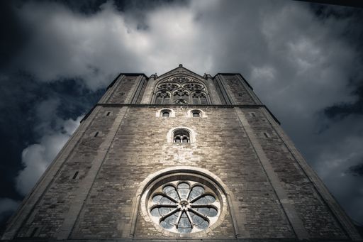 A low angle shot of an old cathedral against a cloudy sky