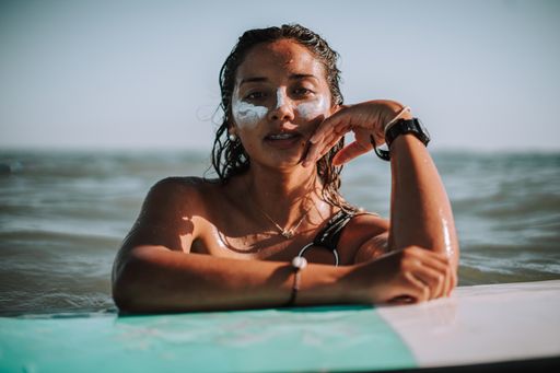 A portrait of a young European female surfer with her hands on her surfboard