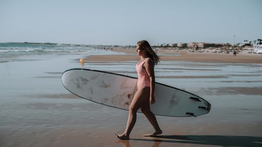 A female surfer holding a surfboard at the beach