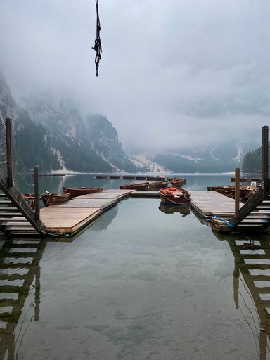 A vertical shot of the wooden dock over Braies lake in the Dolomiti Mountains in Italy