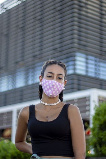 A young female with a medical mask posing at camera on a sunny day - the concept of new normal