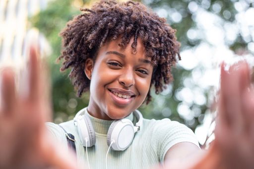 A Portrait of an attractive dark-skinned curly-haired woman taking a selfie, enjoying the spring sun