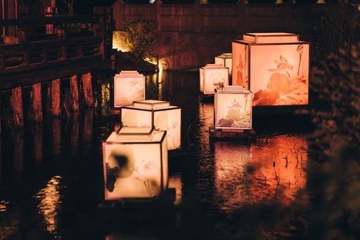 A group of floating Japanese square led lanterns in the pond at night
