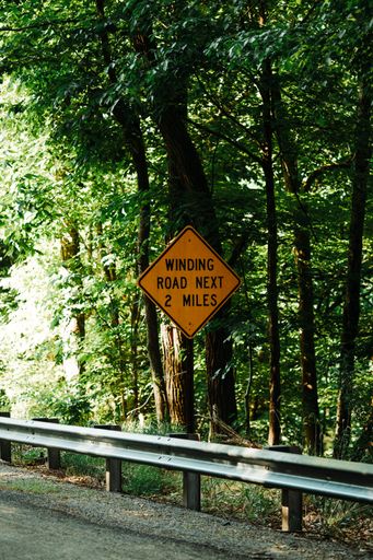 A yellow warning road sign near the fence
