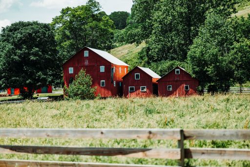 A red barn field with a wooden fence on a sunny day